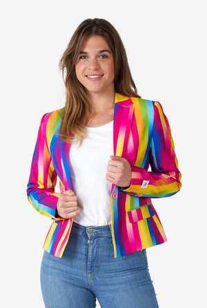 Afbeelding van een vrouw, gekleed in verticaal gestreepte regenboogkleurige damesblazer, wit overhemd en spijkerbroek. Ze houdt de zijkanten van de blazer vast.