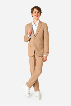 Tienerjongen draagt een stijlvol lichtbruin/beige pak met een wit overhemd en ziet er zelfverzekerd uit. Perfecte formele outfit voor speciale gelegenheden, bruiloften en feesten voor jongens. Volledig lichaamsbeeld.