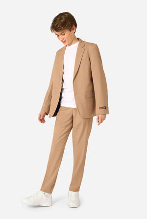 Tienerjongen draagt een stijlvol lichtbruin/beige pak met een wit overhemd en ziet er zelfverzekerd uit. Perfecte formele outfit voor speciale gelegenheden, bruiloften en feesten voor jongens. Volledig lichaamsbeeld.
