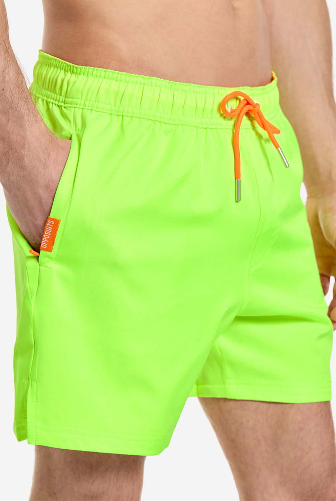Man draagt neon limoengroene zwembroek voor heren, close up