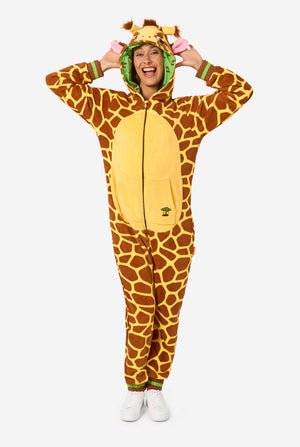 Een lachende vrouw draagt een bruine en gele onesie voor volwassenen die is ontworpen als een giraffe. De onesie heeft een capuchon die op een giraffekop lijkt en giraffedetails, perfect voor gezellig loungen of verkleedfeestjes. De vrouw heeft de capuchon op haar hoofd. Volledig lichaam foto.