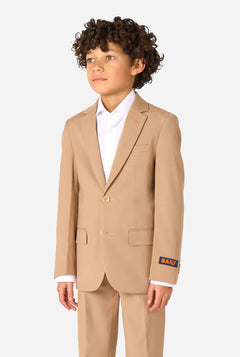 Een kind in een stijlvol lichtbruin/beige pak met een wit overhemd, wegkijkend van de camera. Perfecte formele outfit voor speciale gelegenheden, bruiloften en feestjes voor jongens.