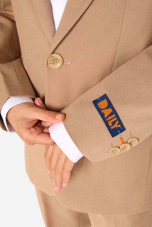 Een kind in een stijlvol lichtbruin/beige pak met een wit overhemd, wegkijkend van de camera. Perfecte formele outfit voor speciale gelegenheden, bruiloften en feestjes voor jongens. Close up van de mouwen.