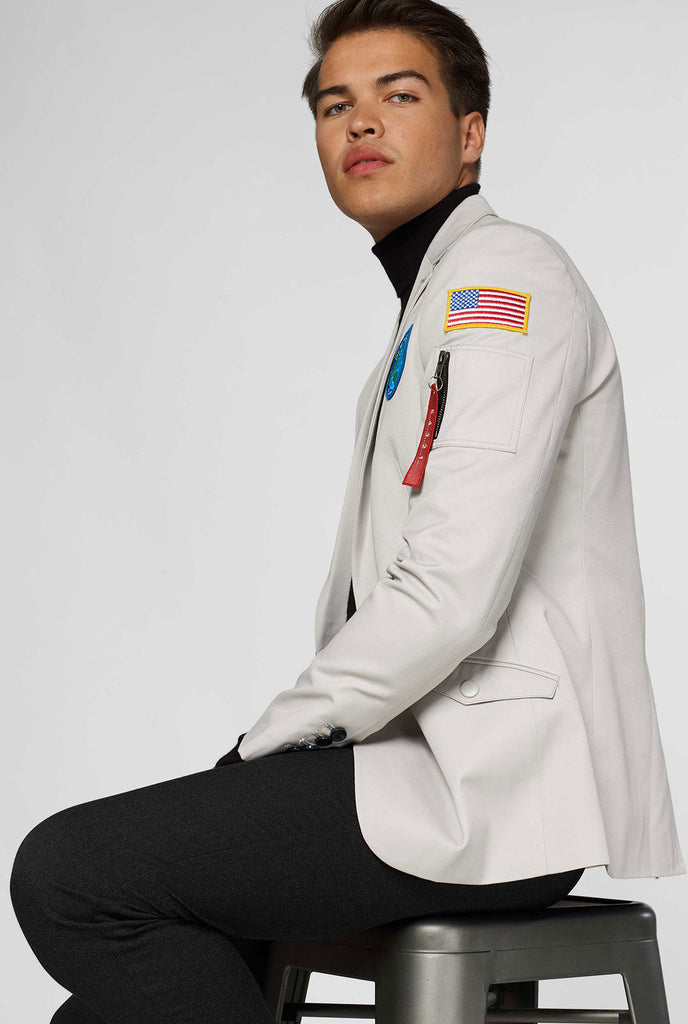 Lichtgrijze blazer met patches met astronaut thema gedragen door de mens die van de zijkant wordt getoond