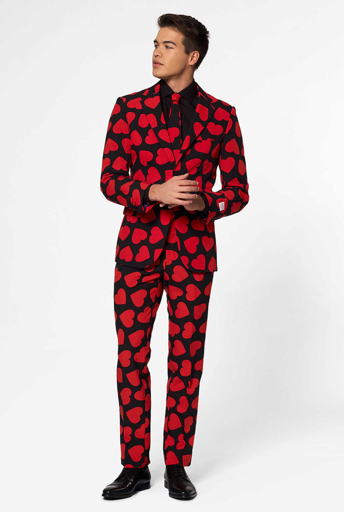 Man draagt ​​een zwart pak met rode harten print
