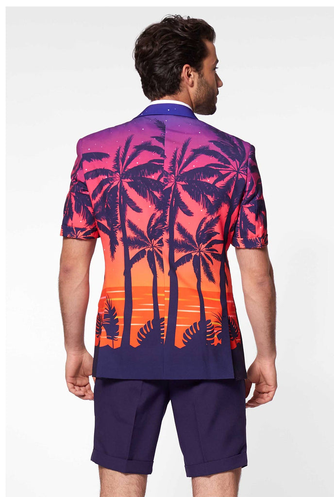 Man draagt ​​een zomerpak met palmen en zonsondergangprint, bekijk vanaf de achterkant