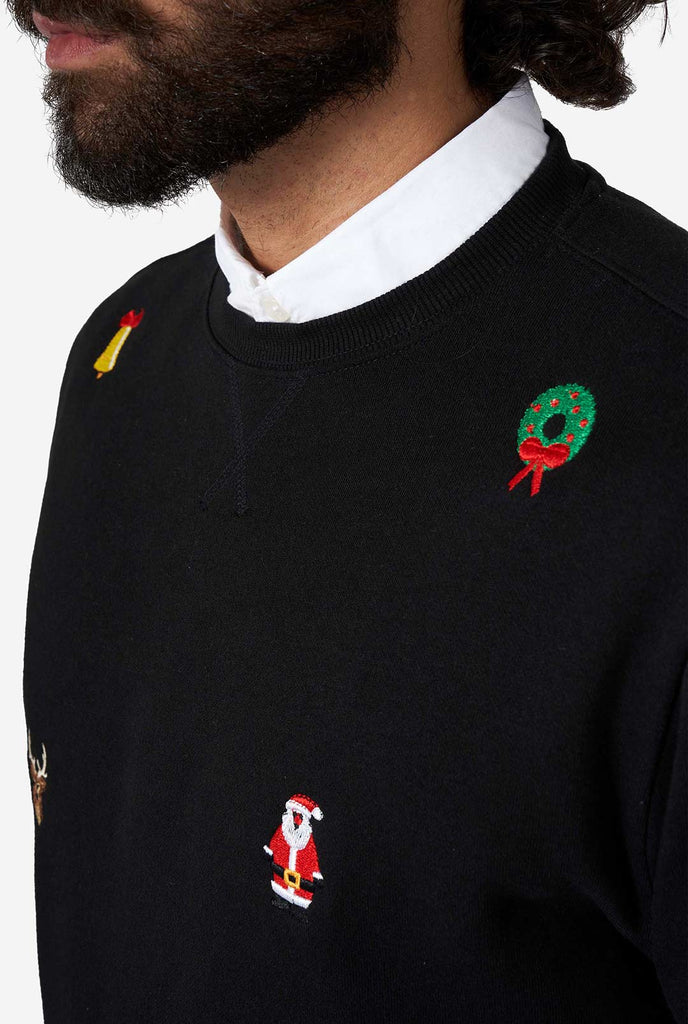 Man draagt ​​een zwarte kersttrui met kerstpictogrammen, close -up
