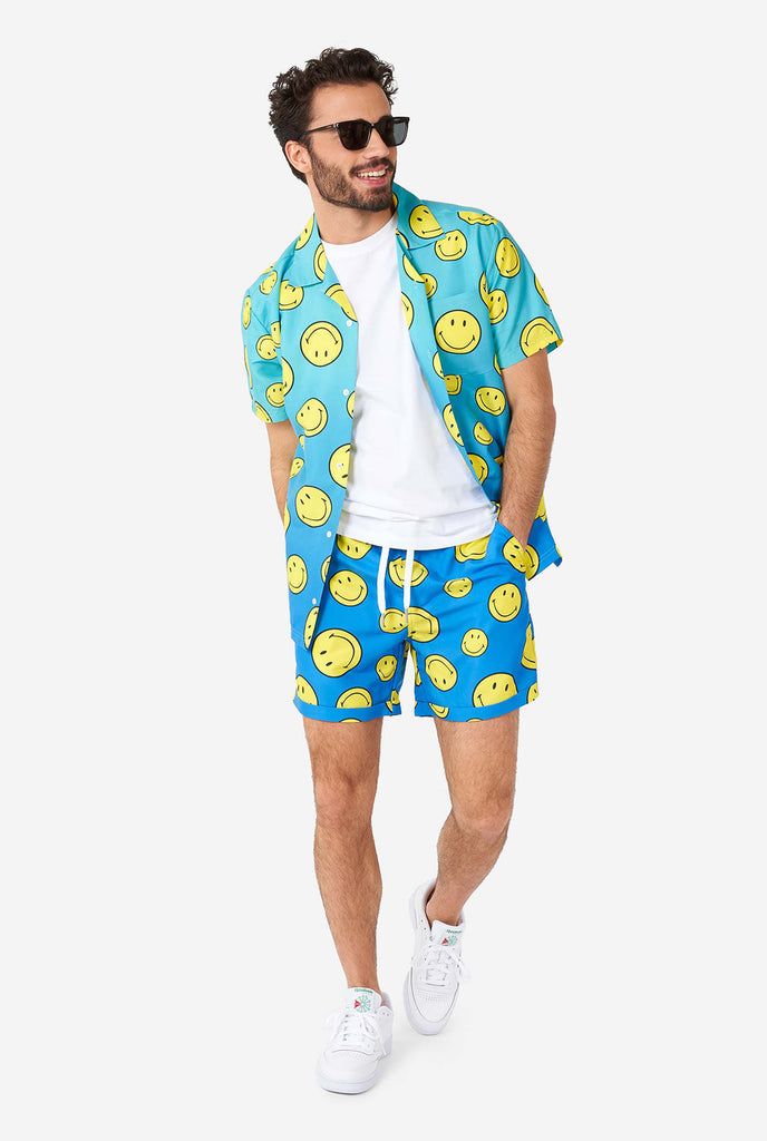 Man draagt ​​een blauwe zomerset, bestaande uit shorts en shirt, met smiley print
