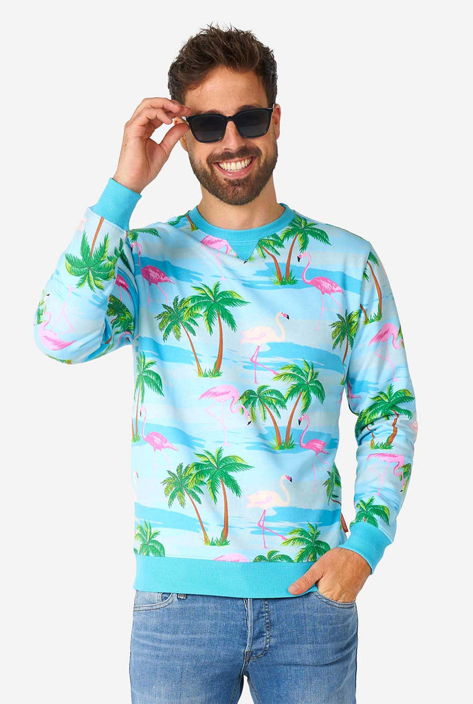 Man draagt ​​een blauwe trui met tropische flamingo -print