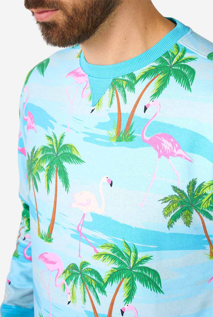 Man draagt ​​een blauwe trui met tropische flamingo -print, close -up