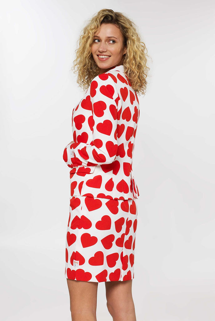 Vrouw die een wit Valentijnsdagpak draagt ​​met rode harten, bekijk vanaf de achterkant