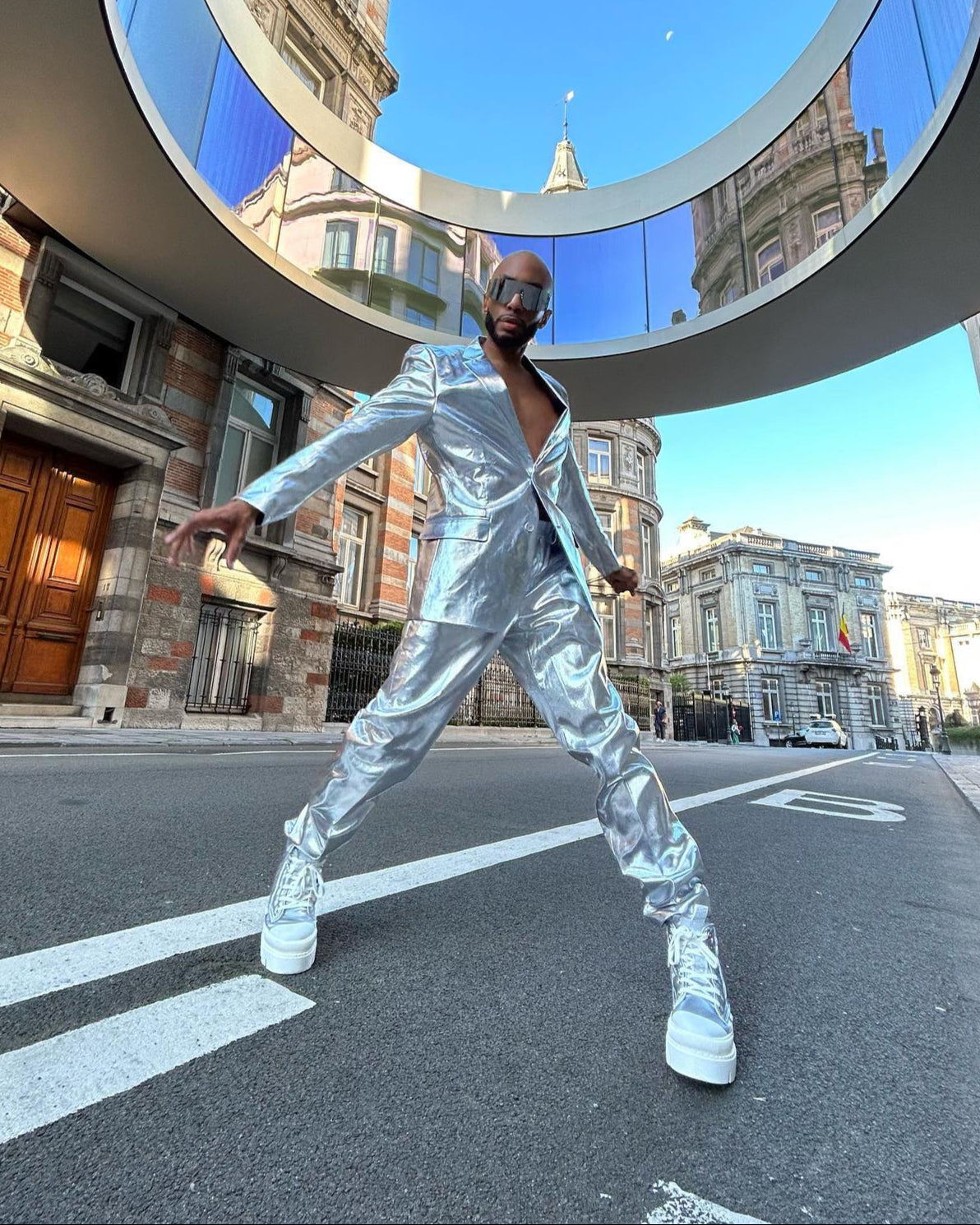 Persoon in een zilveren reflecterende outfit die zich voordeed op een stadsstraat.