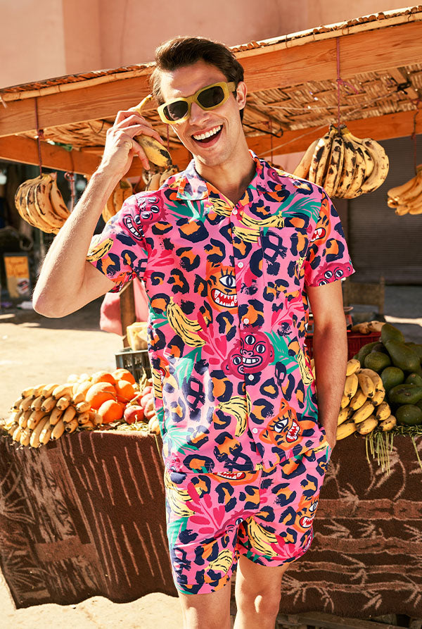 Persoon die een kleurrijke outfit draagt met een levendig patroon, staande voor een fruitkraam.