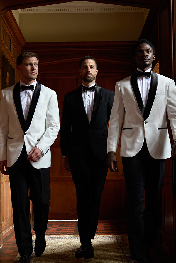 Drie mannen in formele pakken staan in een gang.