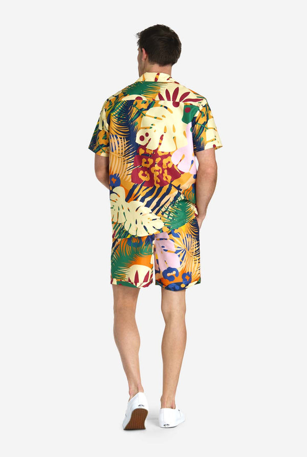 Een man in een tropische zomerset, bestaande uit een kort broekje en een overhemd met knopen, zicht vanaf de achterkant