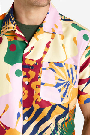 Een man in een tropische zomerset, bestaande uit een kort broekje en een overhemd met knopen