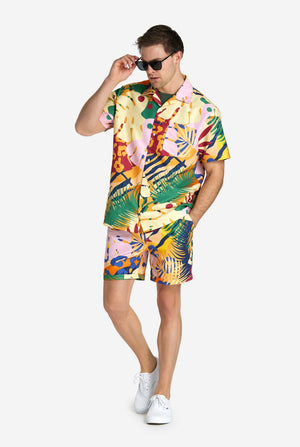 Een man in een tropische zomerset, bestaande uit een kort broekje en een overhemd met knopen