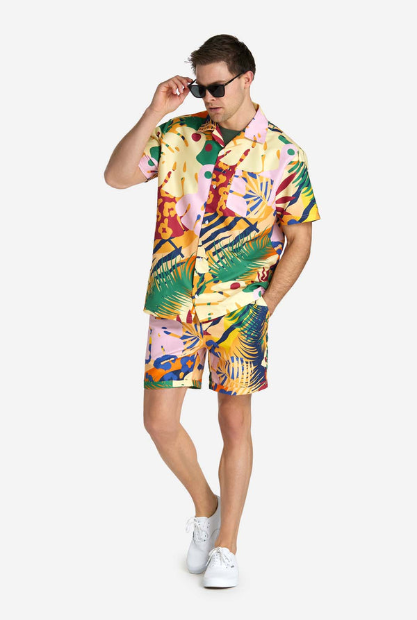 Een man in een tropische zomerset, bestaande uit een kort broekje en een overhemd met knopen