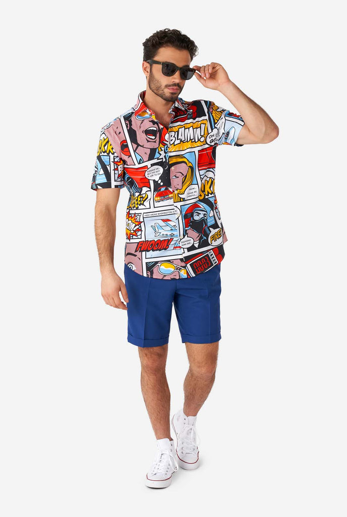 Man draagt ​​zomerhemd met stripboekenprint en blauwe shorts