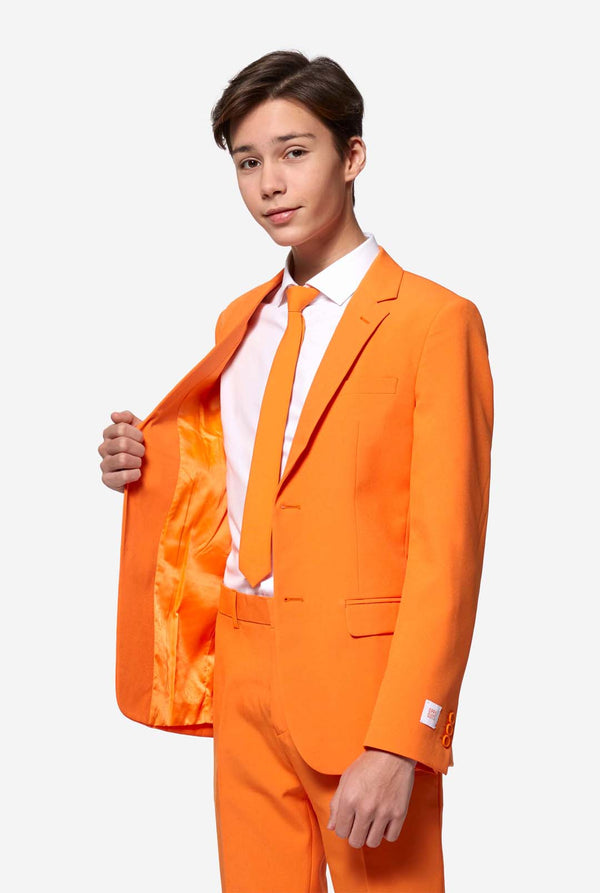 Tiener in formeel oranje pak. Houd een kant van het jasje open.