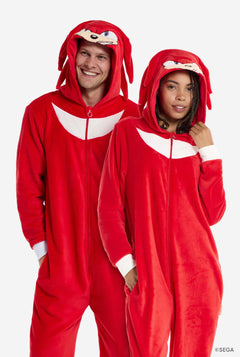Een man en een vrouw dragen een felrode Knuckles the Echidna onesie voor volwassenen van OppoSuits. De leuke en comfortabele onesie heeft een ritssluiting aan de voorkant en een capuchon die is ontworpen om Knuckles' gezicht te imiteren, compleet met expressieve ogen en flodderige dreadlocks. Het pak is overwegend rood, met een wit halvemaanpatroon op de borst, een verwijzing naar Knuckles' iconische look uit de Sonic the Hedgehog-videogameserie.
