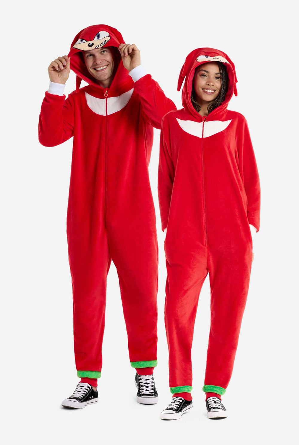 Een man en een vrouw dragen een felrode Knuckles the Echidna onesie voor volwassenen van OppoSuits. De leuke en comfortabele onesie heeft een ritssluiting aan de voorkant en een capuchon die is ontworpen om Knuckles' gezicht te imiteren, compleet met expressieve ogen en flodderige dreadlocks. Het pak is overwegend rood, met een wit halvemaanpatroon op de borst, een verwijzing naar Knuckles' iconische look uit de Sonic the Hedgehog-videogameserie.