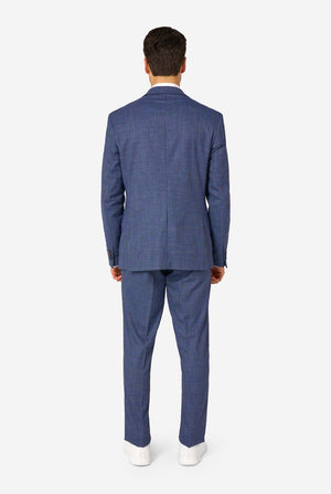 Een man draagt een marineblauw en blauw geruit pak met een wit overhemd. Het pak heeft een moderne pasvorm met twee knopen en klepzakken. Hij staat tegen een effen witte achtergrond. Zicht vanaf de achterkant