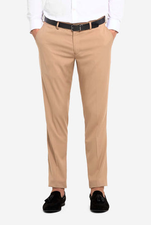 Afbeelding met lichtgrijze achtergrond en man die donker zand mannenpak en wit overhemd draagt. Pak bestaat uit blazer en broek. Gericht op de broek.