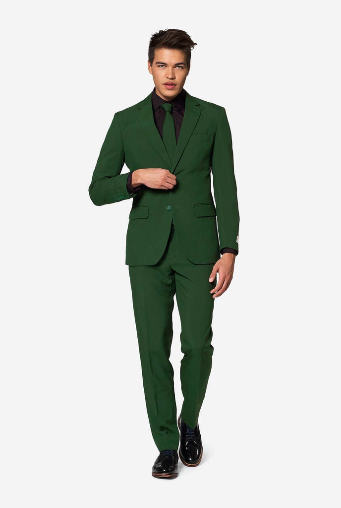 Full body-shot van een man in een OppoSuits Glorious Green herenpak die zelfverzekerd loopt – opvallend groen formeel pak voor moderne gelegenheden.