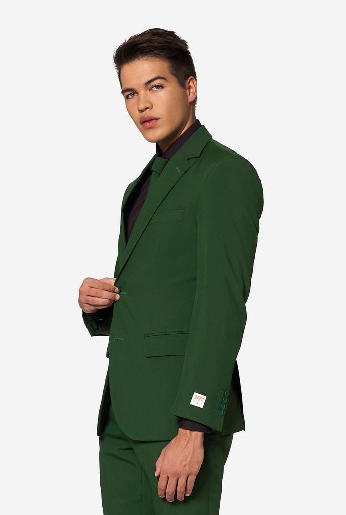 Profiel van een man die een OppoSuits Glorious Green blazer dichtknoopt met zichtbaar OPPO-label: een opvallend en stijlvol groen pak voor heren.