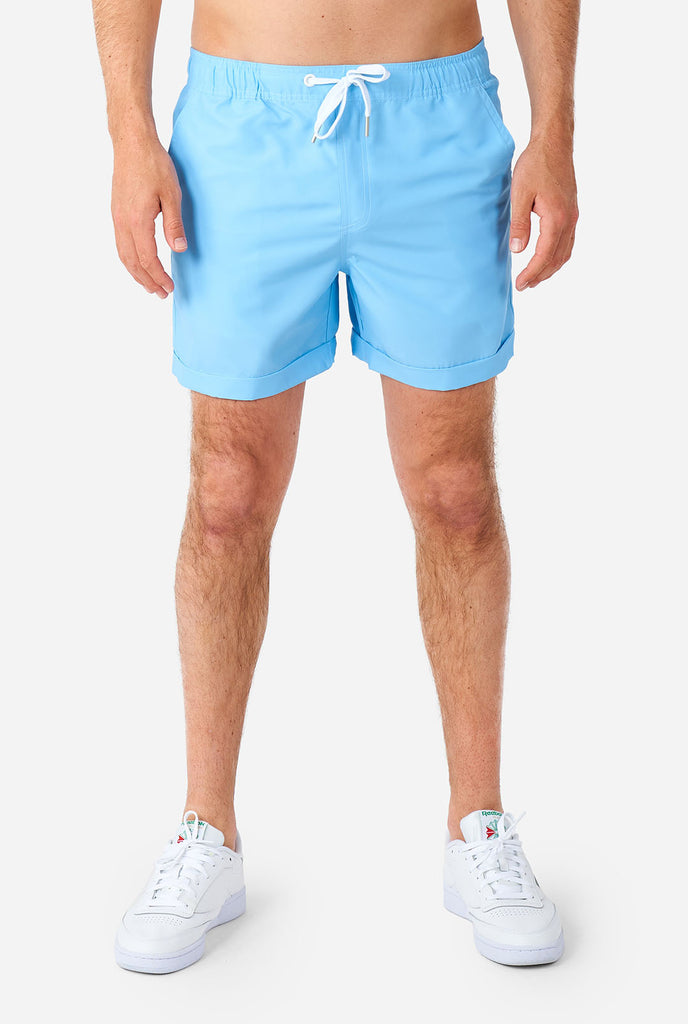 Man in lichtblauwe zomerset, bestaande uit shirt en korte broek