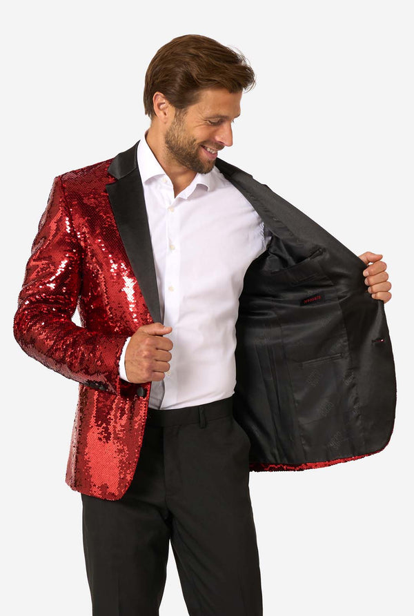Man draagt een glimmend rode paillettenblazer  met zwarte revers.