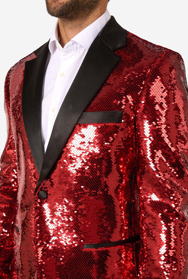 Man draagt een glimmend rode paillettenblazer  met zwarte revers.