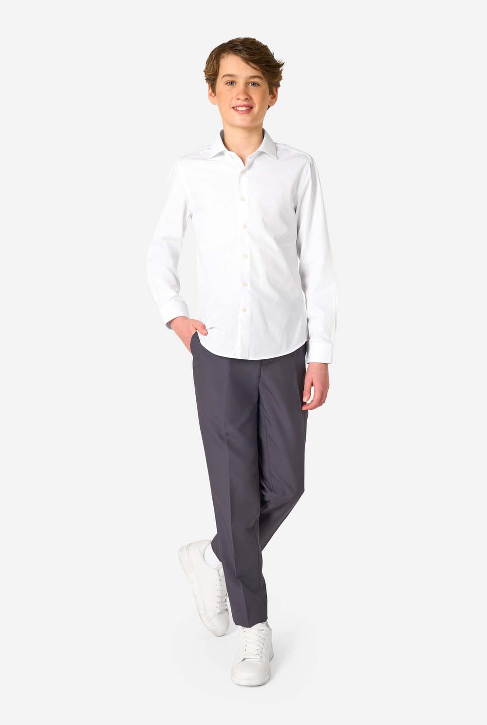 Wit shirt met lange mouwen voor jongens gedragen door een jongen met hand in zak. Draagt ook zwarte broek.