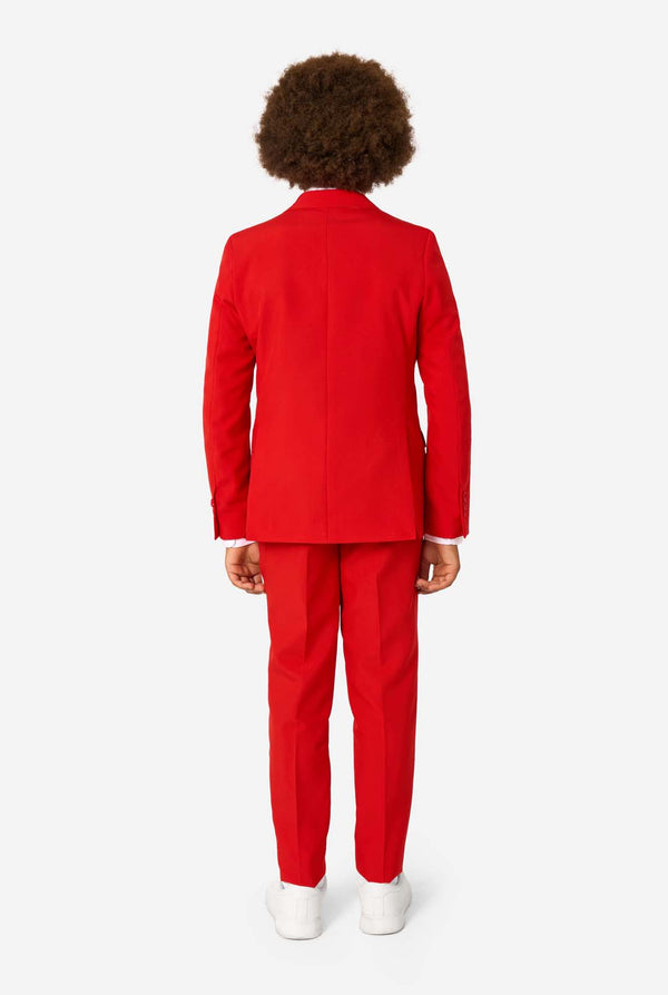 Kind draagt een rood pak met een wit overhemd en een rode stropdas op een witte achtergrond. Zicht vanaf de achterkant