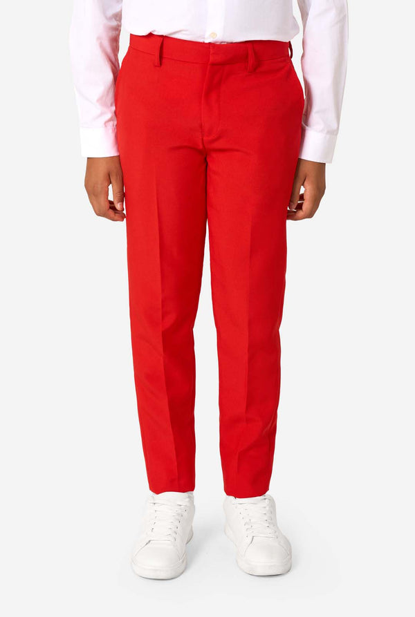 Kind draagt een rood pak met een wit overhemd en een rode stropdas op een witte achtergrond. Close up van de broek
