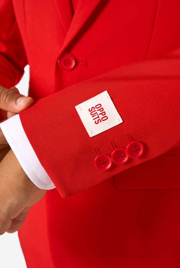 Kind draagt een rood pak met een wit overhemd en een rode stropdas op een witte achtergrond. Close up van de mouwen