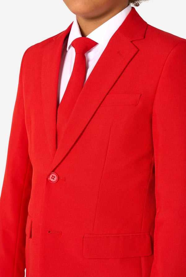 Kind draagt een rood pak met een wit overhemd en een rode stropdas op een witte achtergrond. Close up van de borst