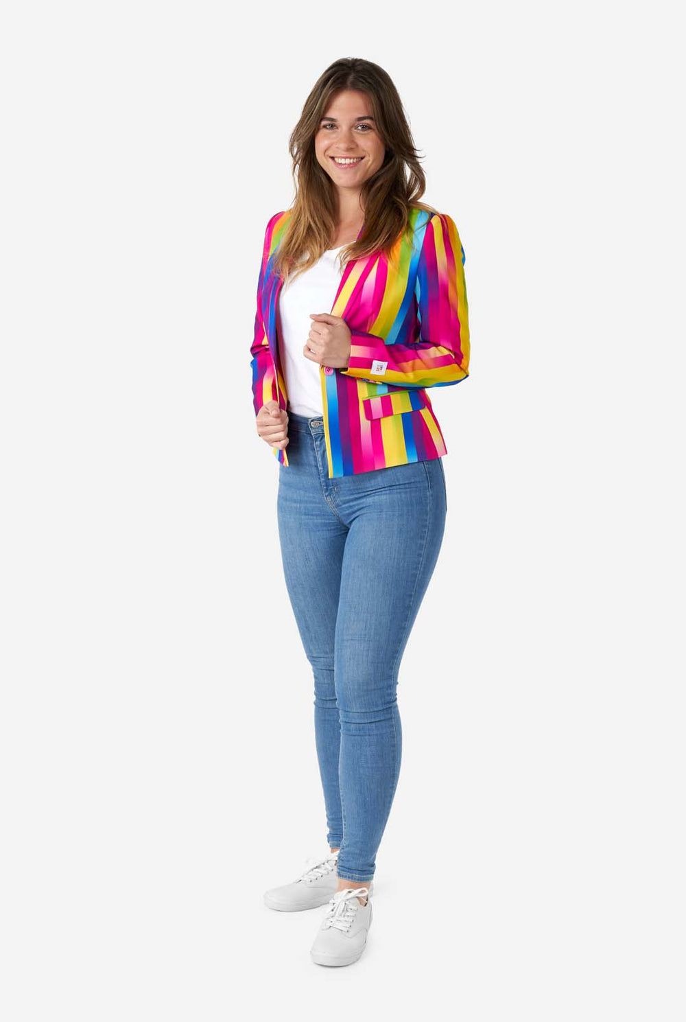 Afbeelding van een vrouw, gekleed in verticaal gestreepte regenboogkleurige damesblazer, wit overhemd en spijkerbroek. Ze houdt de zijkanten van de blazer vast.