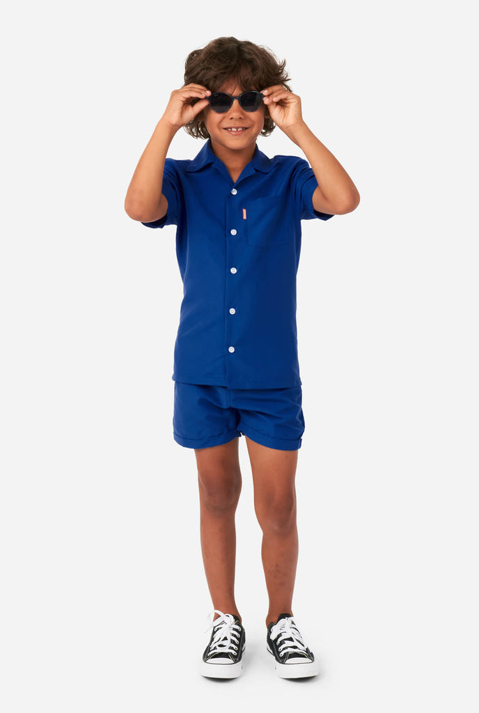 Jongen in donkerblauwe zomerset, bestaande uit korte broek en shirt