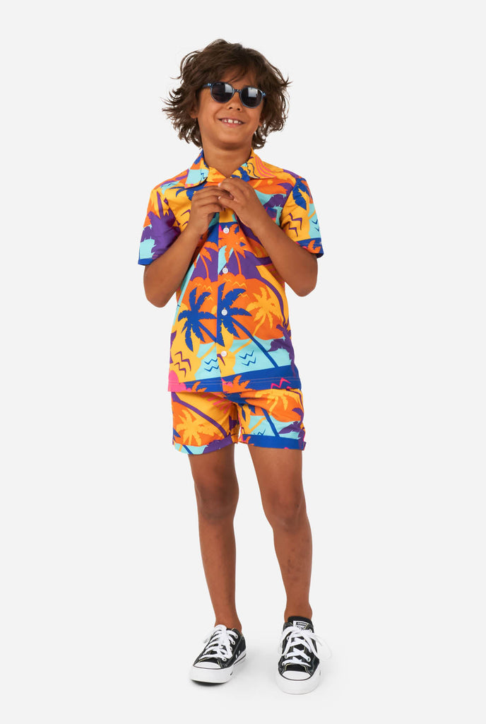 Jongen draagt kleurrijke palm zomerset, bestaande uit korte broek en shirt