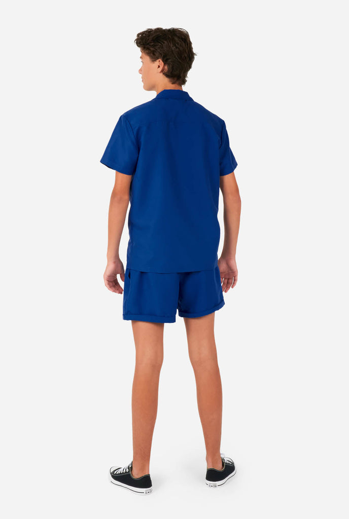 Tiener draagt blauwe zomerset, bestaande uit shirt en short.