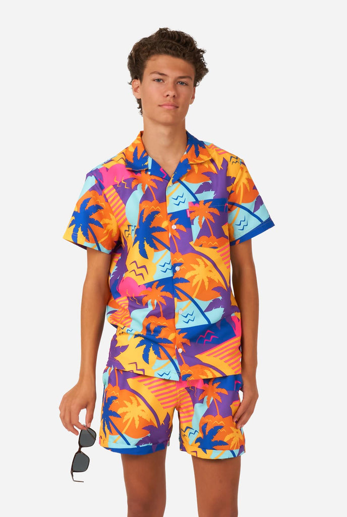 Tiener draagt kleurrijke palmzomerset, bestaande uit shirt en short.