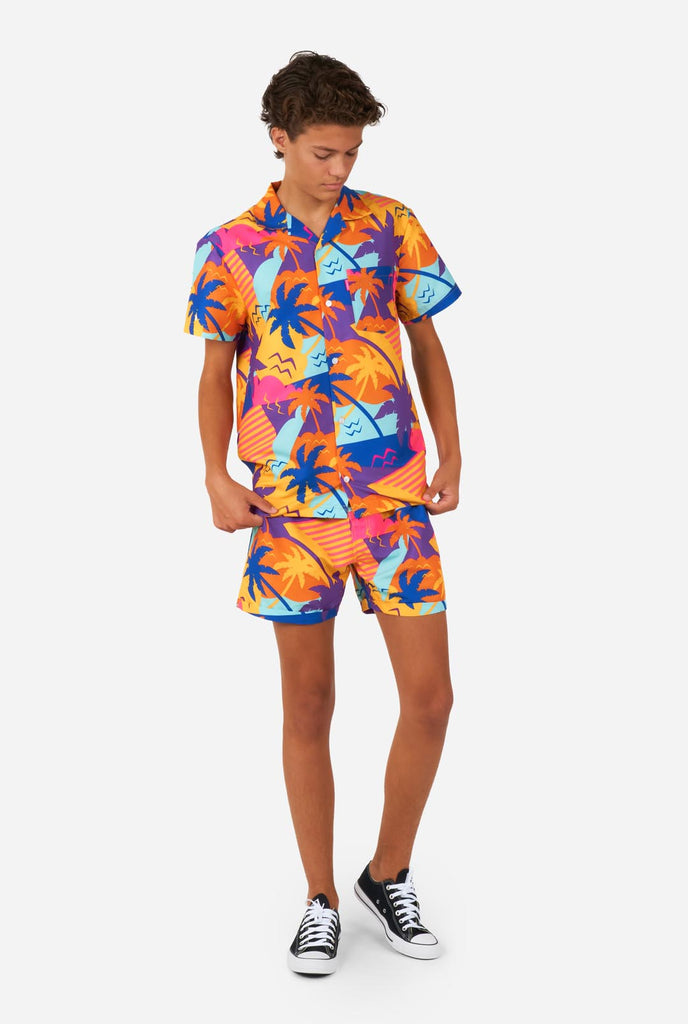 Tiener draagt kleurrijke palmzomerset, bestaande uit shirt en short.