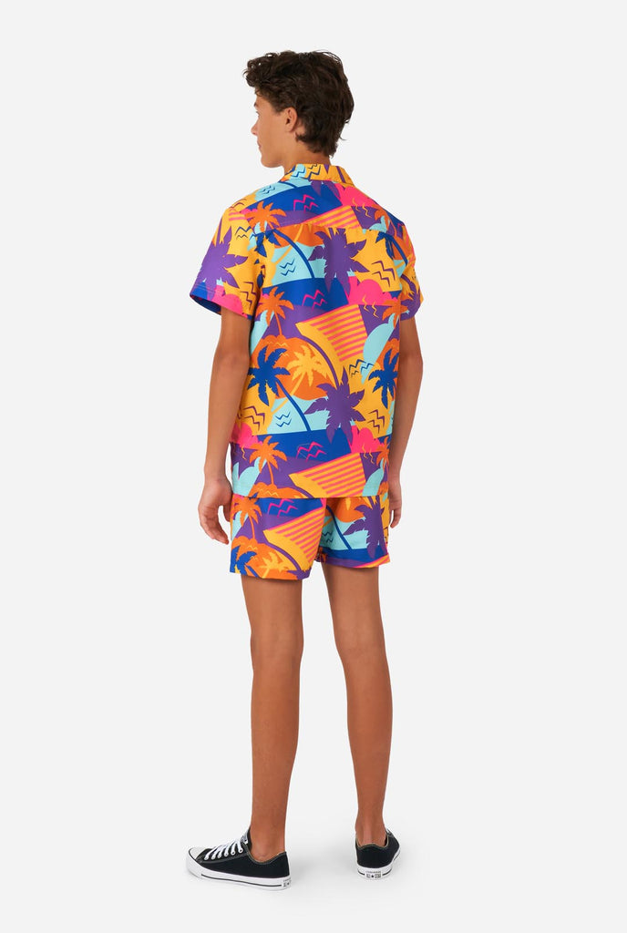 Tiener draagt kleurrijke palmzomerset, bestaande uit shirt en short.