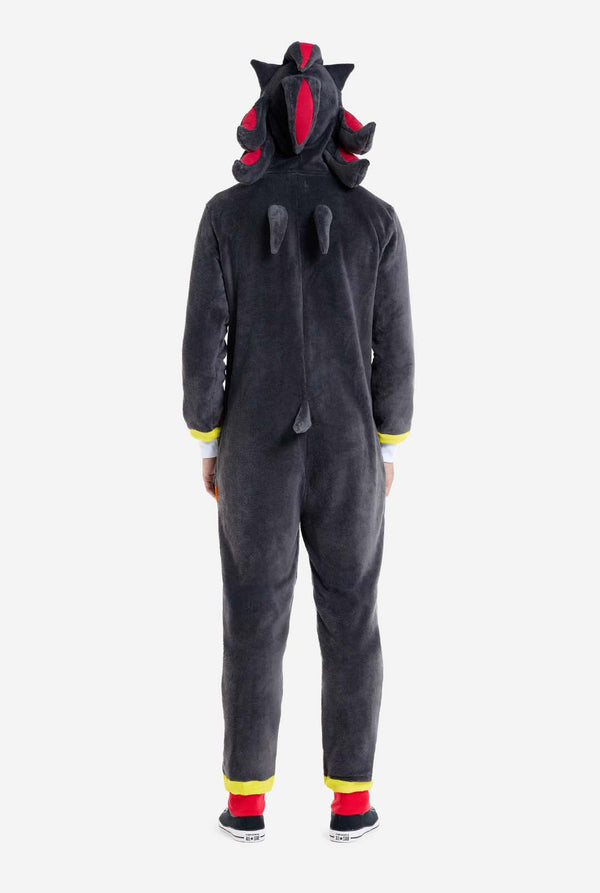 Een man met een pluchen zwarte onesie geïnspireerd op het populaire egelkarakter Shadow, met puntige rode en zwarte accenten op de capuchon, een wit embleem op de borst en gele polsdetails. De onesie is gemaakt van zacht fleecemateriaal en biedt comfort en een speels ontwerp voor cosplay, loungen of thema-evenementen. Uitzicht vanaf de achterkant. Perfect voor fans van gaming of geanimeerde karakters.