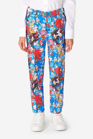 Jonge jongen draagt een levendig Sonic-tienerpak met kleurrijke opdrukken van Sonic the Hedgehog-personages zoals Sonic, Knuckles, Tails en Amy, gecombineerd met een bijpassende stropdas en wit overhemd. Gefocust op de broek