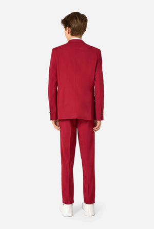 Tienerjongen draagt ​​een stijlvol bordeauxrood pak met een wit overhemd. Perfecte formele outfit voor speciale gelegenheden, bruiloften en feesten voor jongens. Zicht vanaf de achterkant.