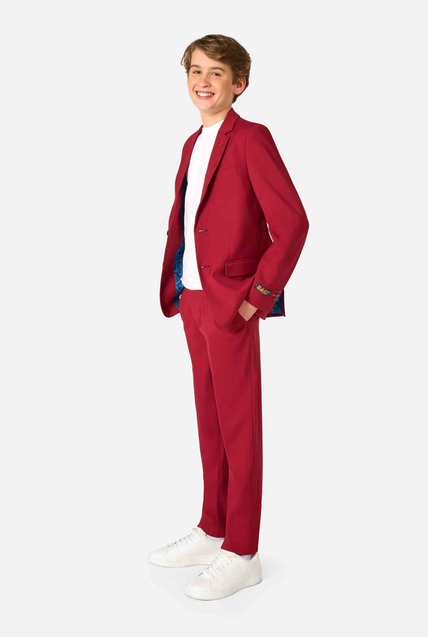 Tienerjongen draagt ​​een stijlvol bordeauxrood pak met een wit overhemd en kijkt zelfverzekerd in de camera. Perfecte formele outfit voor speciale gelegenheden, bruiloften en feesten voor jongens.