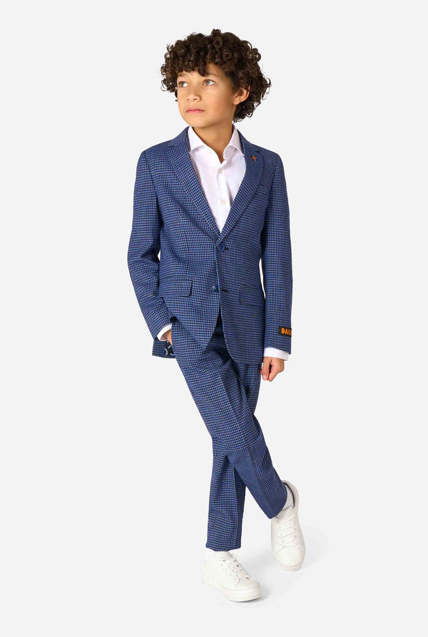 Een jongen, gekleed in een marineblauw en blauw geruit pak met een wit overhemd. Het pak heeft een moderne pasvorm met twee knopen en klepzakken. Hij staat tegen een effen witte achtergrond. Volledig lichaamsbeeld.